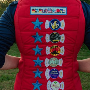 Könnte beinhalten: Rote Steppweste mit blauen Sternaufnähern und Marathon-Event-Aufnähern. Aufnäher sind "WORLD MARATHON", "BOS 26.2 2022", "Chi Marathon 2022", "Berlin 26.2 2023", "NYC 2024", "London Marathon 2024" und "Tokyo Marathon 2024".