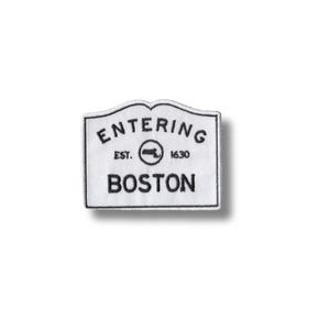 Puede incluir: Parche blanco bordado con texto negro que dice "Entering Boston" con un pequeño icono de cañón y el texto "Est. 1630".
