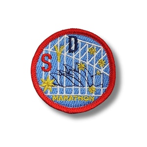 May include: A blue and white embroidered patch with the text "Sydney Marathon" and a depiction of the Sydney Opera House. The patch has a red border.