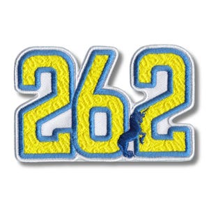 May include: Embroidered patch displaying the number "262" in yellow with a blue border and a blue unicorn silhouette. The patch is set against a white background, suitable for clothing or accessories.