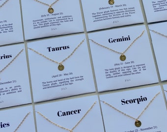 May include: Twelve white cards with gold chains and charms representing the twelve zodiac signs. Each card features the name of the sign, the dates of the sign, and a brief description of the sign's characteristics. The cards are arranged in two rows of six.