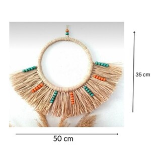 May include: A beige macrame wall hanging, 50 cm wide and 35 cm tall, with a circular design. It features a fringe at the bottom and is adorned with turquoise and orange beads. The natural, earthy tones create a bohemian aesthetic.