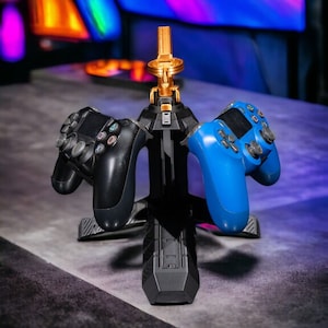 May include: A black and gold controller stand with three slots for controllers. Two controllers are on the stand, one black and one blue.