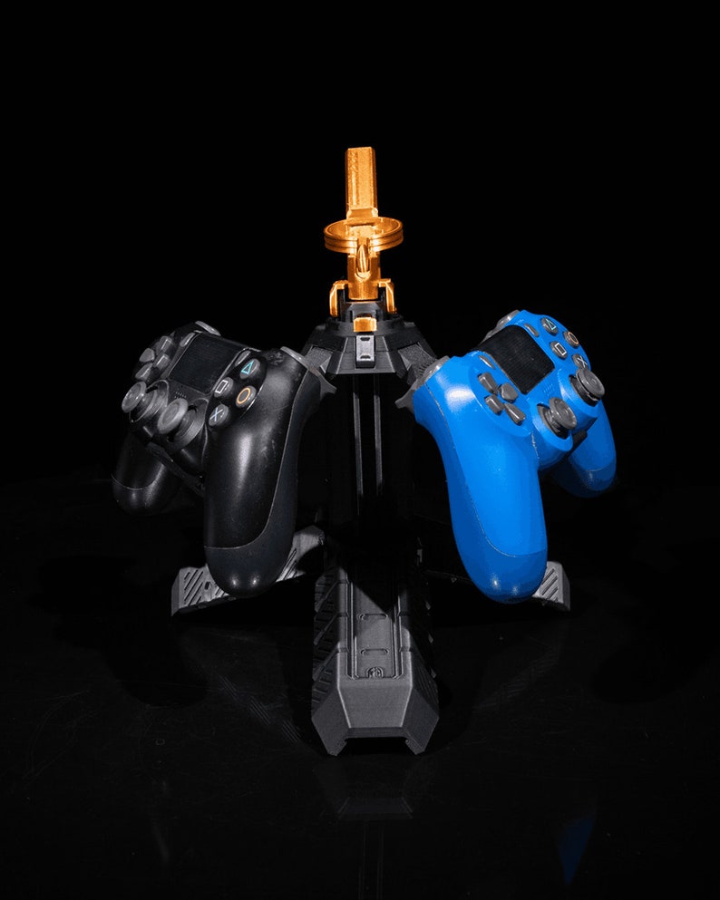 May include: A black and blue video game controller stand with three controllers. Two of the controllers are black and one is blue.