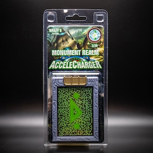 May include: A packaged AccelCharger collectible card from the Monument Realm series. The card is gray with a gold clasp and a green circuit design. The packaging includes the text "KRAZY 8 CUSTOMS" and "MONUMENT REALM ACCELECHARGER".