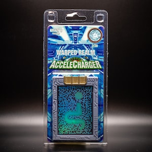 May include: A packaged AccelCharger toy from the Warped Realm series. The card-shaped toy has a blue and gray design with a gold-colored top. The packaging features the text "WARPED REALM ACCELECHARGER" and "KRAZY 8 SYSTEMS".