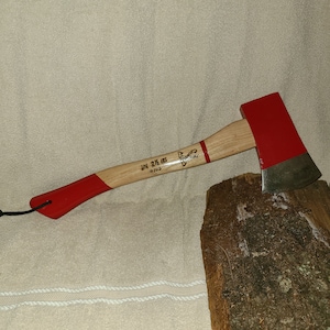 May include: A red and wooden axe with a black handle and a red painted head. The axe is labeled "2 1/2 LBS #163".