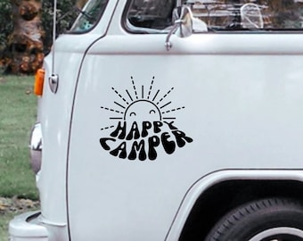 Może przedstawiać: Biały, zabytkowy van z czarną naklejką z napisem "Happy Camper" i wzorem słońca z uśmiechniętą buźką.