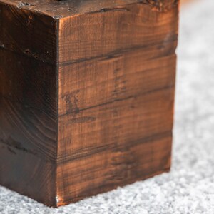 A close up detail of a dark wooden doorstop created from four layers of wood on grey carpet.