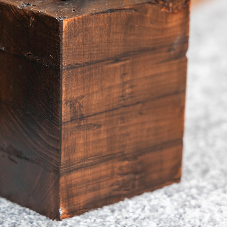 A close up detail of a dark wooden doorstop created from four layers of wood on grey carpet.