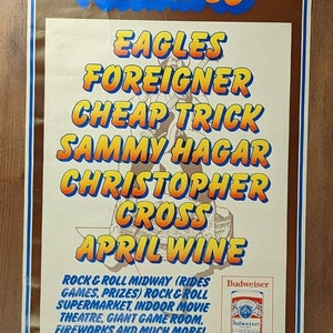 Könnte beinhalten: Ein Vintage-Poster, das das Texas World Music Festival 80 bewirbt, mit braunem Hintergrund und einem blauen und gelben Stern. Das Poster listet die Musikacts auf, die beim Festival auftreten: Eagles, Foreigner, Cheap Trick, Sammy Hagar, Christopher Cross und April Wine. Das Poster enthält auch das Datum und den Ort des Festivals: Samstag, 21. Juni, Cotton Bowl, Dallas, Tx. Das Poster enthält auch das Budweiser-Logo.
