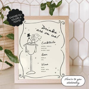 May include: A white framed sign with black text and illustrations. The sign says "Drinks are on us!" and lists cocktails, beer, and wine options. The sign is on a white tiled surface.