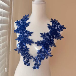 May include: Two blue floral lace appliques with a delicate floral design. The appliques are perfect for adding a touch of elegance to any project.