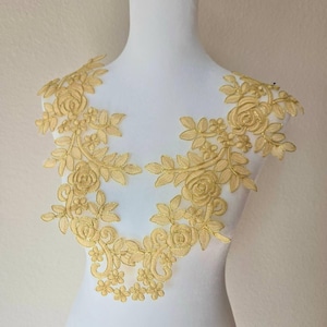 May include: Gold floral lace applique with a delicate design featuring roses and leaves. This lace trim is perfect for adding a touch of elegance to clothing, accessories, or home decor projects.