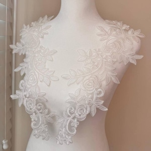 May include: Two white lace appliques with floral designs, perfect for adding a touch of elegance to clothing or crafts.