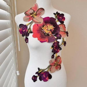 May include: A large floral applique with pink, purple, and yellow flowers. The applique is made of fabric and is perfect for adding a touch of elegance to any project.