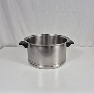May include: A stainless steel cooking pot with a polished metallic finish, featuring two black heat-resistant side handles and a wide, open top. The pot has a cylindrical body with a reinforced base rim, designed for stovetop use.