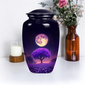 May include: A black urn with a glossy finish, featuring a celestial design. The artwork depicts a full moon, a purple tree, and a field of flowers under a starry night sky. The urn is a decorative item.