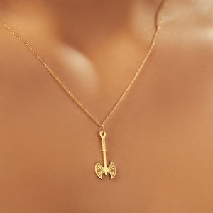 May include: A gold necklace with a pendant shaped like an axe. The axe has a detailed design and is a popular symbol of strength and power.