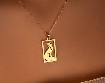Peut inclure: Un collier en chaîne dorée avec un pendentif représentant une silhouette de renard dans un cadre rectangulaire.