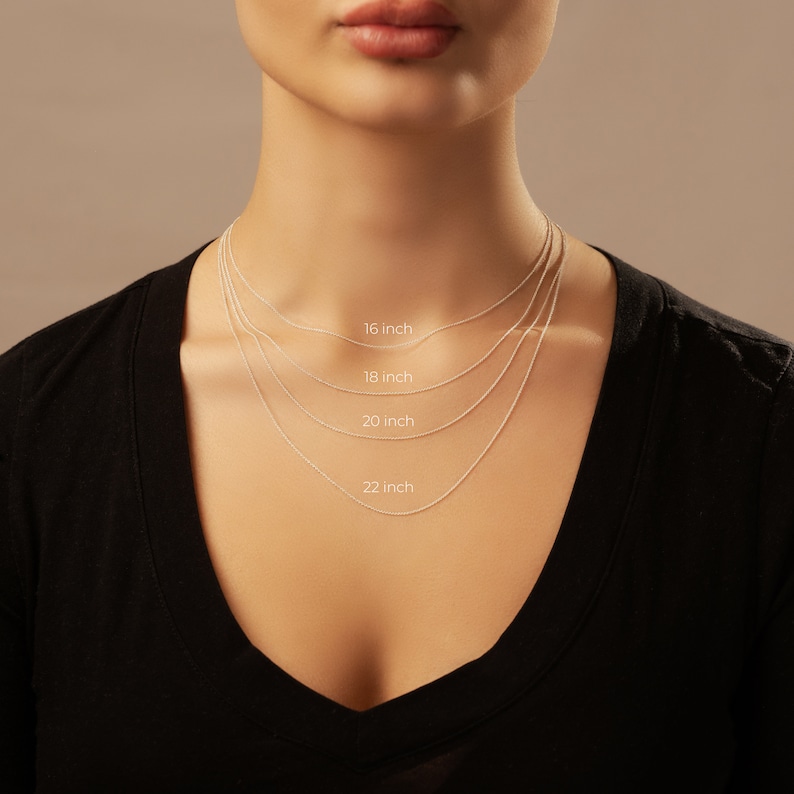 May include: A model wears a silver chain necklace in four different lengths: 16 inches, 18 inches, 20 inches, and 22 inches. The model is wearing a black shirt.