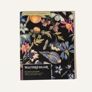 May include: A pad of watercolor paper by Paige Tate & Co. featuring a black cover with a botanical and seashell print. The text reads WATERCOLOR, WATERCOLOR PAPER, 20 Sheets, 8 in x 10 in (20.3 cm x 25.4 cm), Cold Press, pH Neutral, Wood-Free Paper.