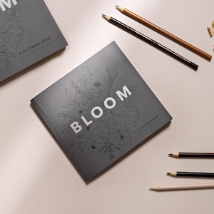 May include: A gray coloring book with a floral design and the word "BLOOM" in white text. The book is titled "A Coloring Book featuring vibrant pages".