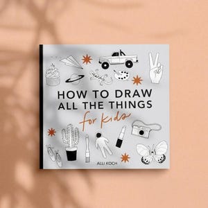 May include: A square book titled How to Draw All the Things for kids by Alli Koch. The light gray cover features black line art illustrations of a cupcake, paper airplane, truck, lizard, palette, hand, cactus, brush, astronaut, lipstick, camera, and butterfly.