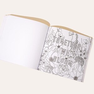 May include: Open coloring book with the text "TOGETHER WE BLOOM" surrounded by floral line art. The book is open to a blank page and a page with detailed flower illustrations. The cover is a light tan color.