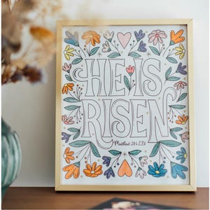 Perforated pages are perfect for framing your colored in pages. This shows a picture of a framed coloring page that says "He is Risen".