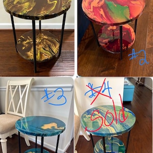 May include: A set of three small, round side tables with a two-tiered design. Each table features a unique, colorful, abstract epoxy resin top and a black metal frame. The tables are suitable for a living room or bedroom.