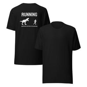 May include: Black t-shirt with the word "RUNNING" above a graphic of a dinosaur chasing a stick figure runner. The text "SOMETIMES WE JUST NEED A LITTLE MOTIVATION" is below the graphic. The shirt is made of a soft material.