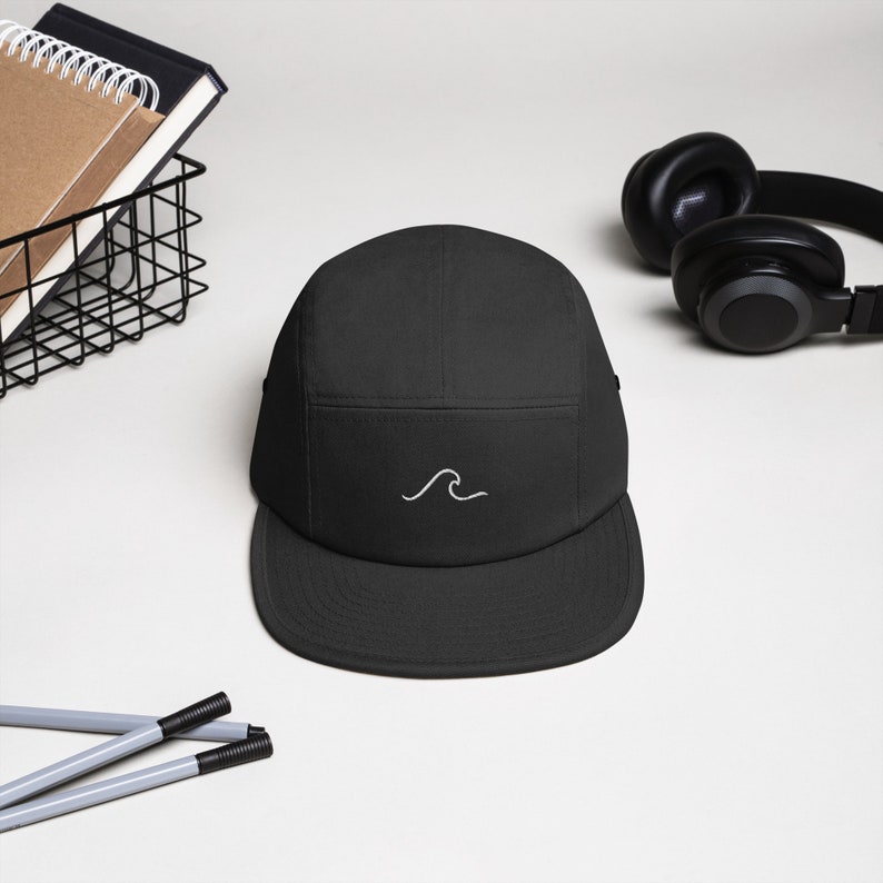 May include: A black 5-panel cap with a white wave design embroidered on the front.