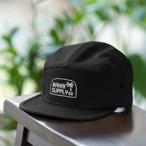 May include: A black 5-panel hat with a white embroidered logo that says "MAKAI SUPPLY CO." and a palm tree graphic.