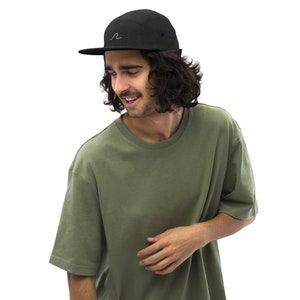 May include: A person wearing a black 5-panel cap with a white wave logo and a green t-shirt.
