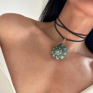 May include: A black choker necklace with a green and brown seashell pendant.