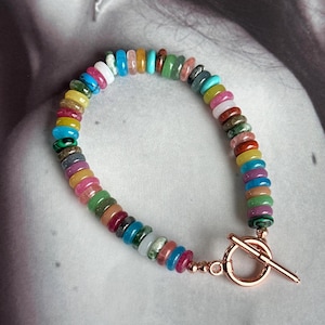Könnte beinhalten: Ein farbenfrohes Armband aus verschiedenen Edelsteinperlen mit einem roségoldenen Verschluss.