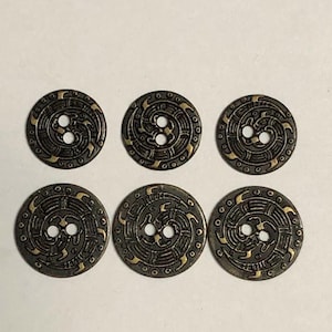 May include: A set of six circular buttons featuring a dark bronze finish with raised gold-toned spiral patterns and small circular accents. Each button has two central holes for attachment and a detailed, symmetrical design on the surface.