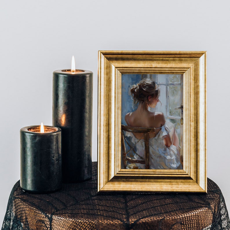 May include: A framed painting of a woman sitting in a chair, facing away from the viewer. The painting is in a gold frame and is on a black lace tablecloth with two black candles.