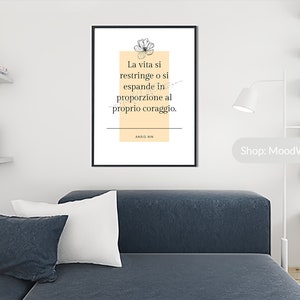 May include: A black framed print with a white background and a beige rectangle in the center. The rectangle contains a quote in Italian that reads "La vita si restringe o si espande in proporzione al proprio coraggio." The quote is attributed to Anais Nin.