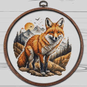 May include: A cross-stitch pattern of a red fox standing in a mountain landscape. The fox is facing the viewer with its head tilted slightly to the side. The background is a mix of brown, green, and blue colors, representing mountains, trees, and sky.