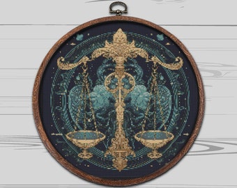 May include: A circular embroidery hoop with a dark blue background and a gold and teal design of the astrological symbol for Libra. The design features a scale with two bowls and a stylized floral pattern.