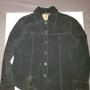 May include: A black suede button-up shirt with a star-shaped logo on the left side of the chest.