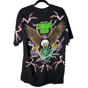 May include: Black t-shirt with a graphic of a bald eagle holding a cabbage. The text "Sopronice's Cabbage Patch 1995 Bike Week" is printed on the shirt.