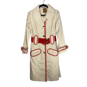 May include: A white trench coat with red piping and a red patent leather belt. The coat has a Peter Pan collar and gold buttons.