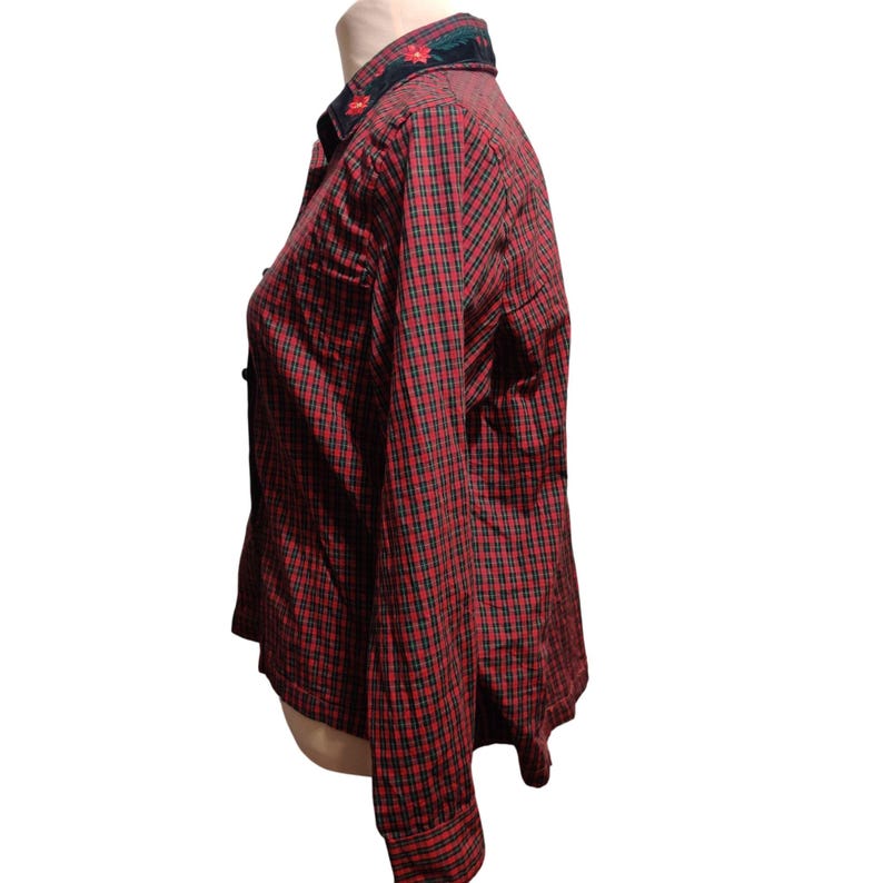 K&ouml;nnte beinhalten: Rot-schwarz kariertes Button-Down-Hemd mit langen &Auml;rmeln. Der Kragen ist dunkelgr&uuml;n mit roter Blumenstickerei. Das Hemd wird auf einer Schaufensterpuppe pr&auml;sentiert, die das Seitenprofil und die Details des Kleidungsst&uuml;cks zeigt.