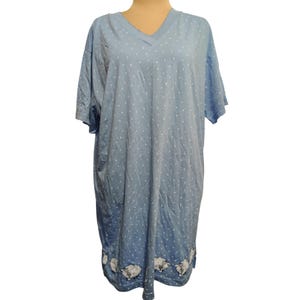May include: A light blue short-sleeved nightgown featuring a V-neckline and a white polka dot pattern throughout. The hem of the garment is decorated with a repeating graphic print of small white sheep with black details arranged in a horizontal row.