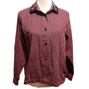 K&ouml;nnte beinhalten: Ein lang&auml;rmliges rot kariertes Hemd mit schwarzen Kn&ouml;pfen und einem floral bestickten Kragen. Das Hemd ist zugekn&ouml;pft und hat einen klassischen, l&auml;ssigen Stil. Das Karomuster ist eine Mischung aus Rot und Schwarz.