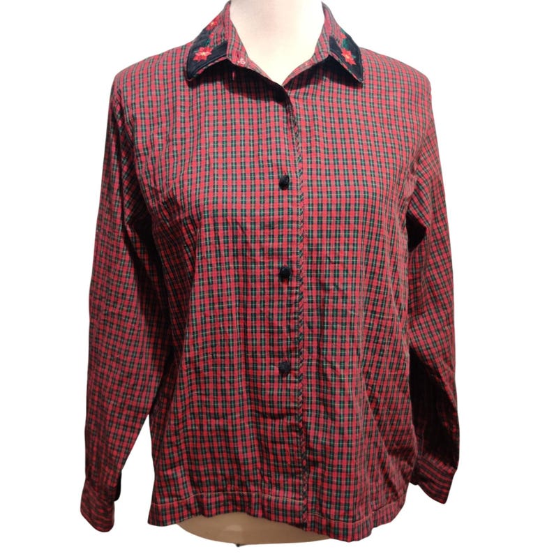 K&ouml;nnte beinhalten: Ein lang&auml;rmliges rot kariertes Hemd mit schwarzen Kn&ouml;pfen und einem floral bestickten Kragen. Das Hemd ist zugekn&ouml;pft und hat einen klassischen, l&auml;ssigen Stil. Das Karomuster ist eine Mischung aus Rot und Schwarz.