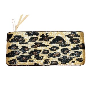 May include: A rectangular clutch with a leopard print design. The clutch is primarily beige with black and brown spots. A small, light-colored tassel hangs from the top corner. The clutch is likely made of beads.